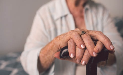 An elderly woman holds her cane