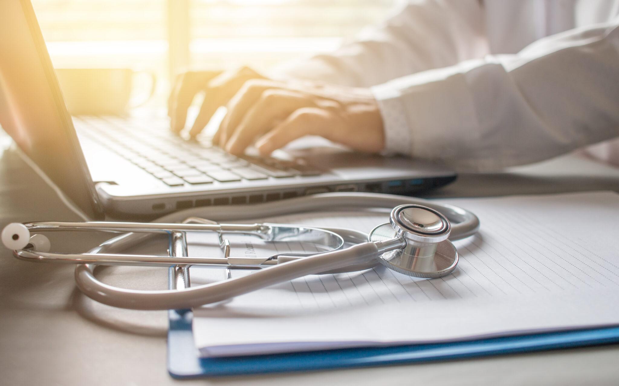 Stethoscope on prescription clipboard and Doctor working an Lapt