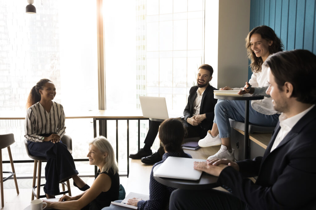 Six professionals engaged in lively informal meeting in modern office